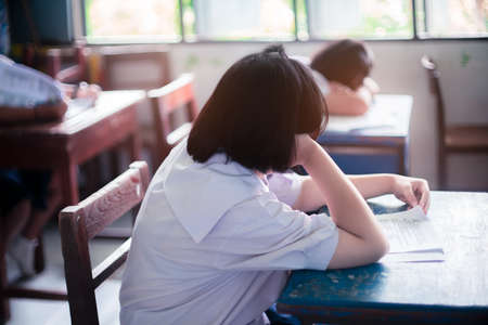 Tired uniform student sleeping in a exam test classroomの写真素材