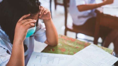 Students wearing mask for protect  corona virus or covid-19 and doing exam answer sheets exercises in classroom of school with stress.の写真素材