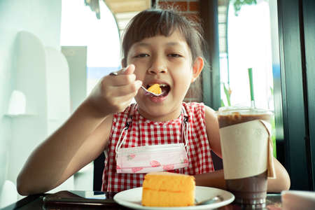 Asian little child girl eating chiffon cakeの写真素材