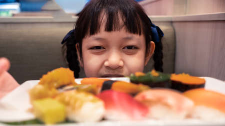 Asian little child girl  eating sushi in a cafeの写真素材