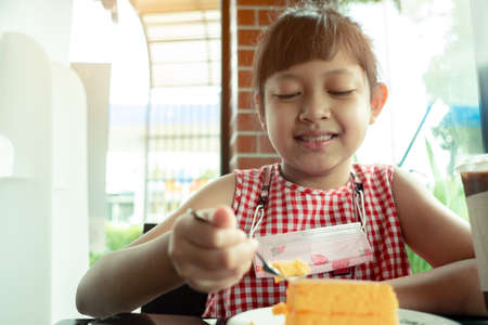 Asian little child girl eating chiffon cakeの写真素材