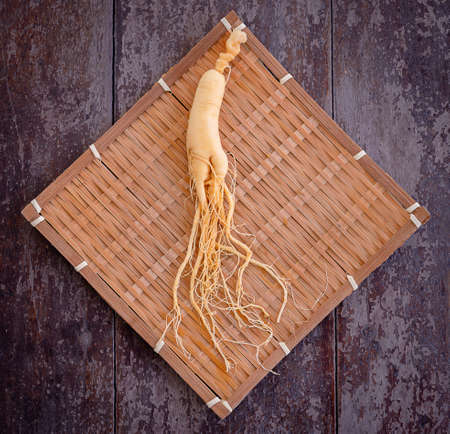 Fresh ginseng on bamboo weave with the wood backgroundの写真素材