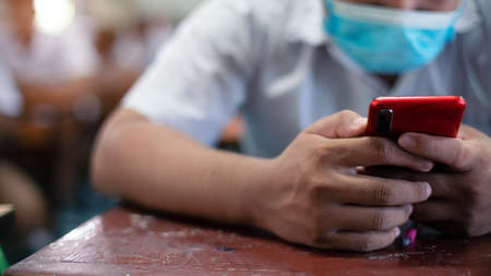 Uniform students are study online  or test exam by using smartphone and wearing protective facemask in classroomの写真素材