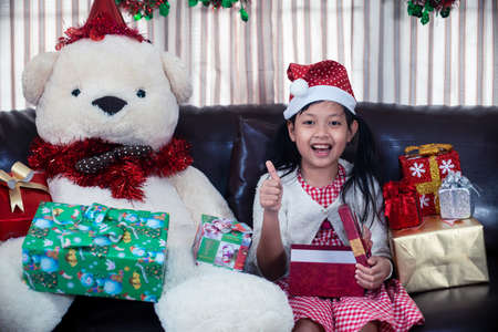 Xmas Festive asian little girl smile and open a gift box at homeの写真素材