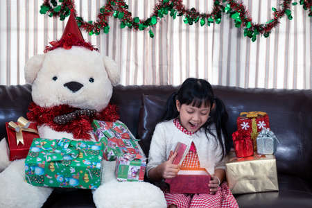 Xmas Festive asian little girl surprise and open a gift box at homeの写真素材