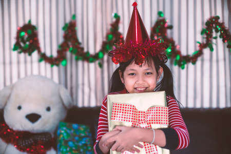 Xmas Festive asian little girl smile and hugging a gift box at homeの写真素材