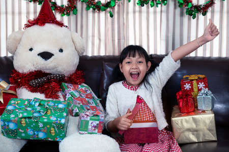 Xmas Festive asian little girl surprise and open a gift box at homeの写真素材