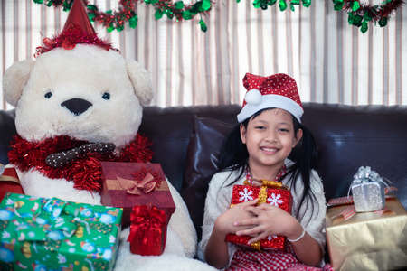 Xmas Festive asian little girl smile and hugging a gift box at homeの写真素材