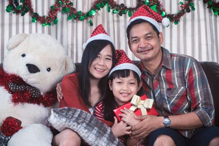 Asian family in Christmas interior.Happy mother father and  daughter holding a gift box with smileの写真素材