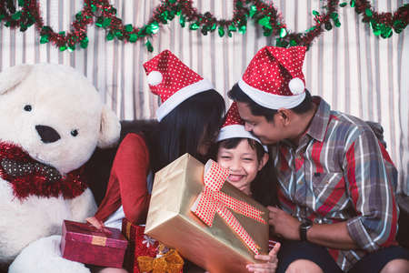 Asian family in Christmas interior.Happy parents kissing daughter and giving xmas presentの写真素材