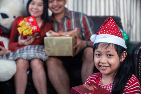 Asian family in Christmas interior.Happy daughter mother and father holding a gift box with smileの写真素材