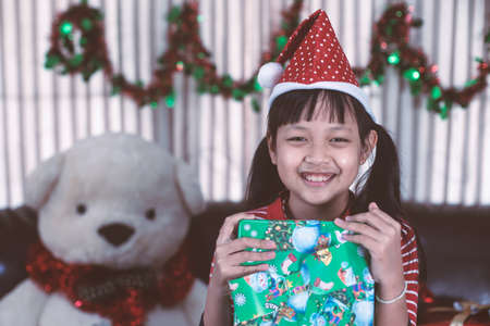 Asian little girl holding a gift box with smile and happy in christmas dayの写真素材