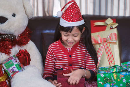 Asian little girl ready to open a gift box with smile and happy in christmas dayの写真素材