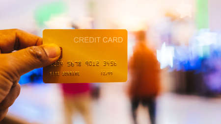 Hand is holding a credit card walking at shopping mallの写真素材
