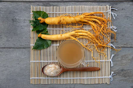 Fresh Ginseng root with a cup of hot tea on a bamboo matの写真素材