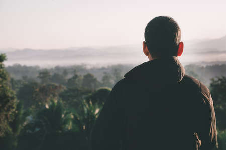 Traveler man looking a sunrise ,fog and landscape on a top of a mountainの写真素材