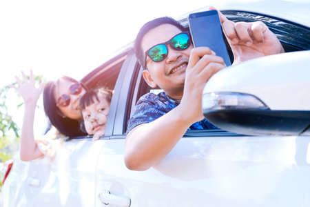 Happy asian family taking selfie in car