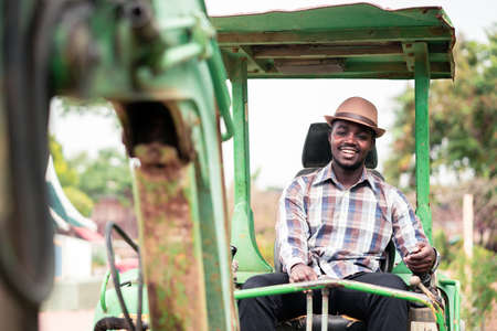 African worker driving heavy construction equipment backhoe with smile and happyの写真素材