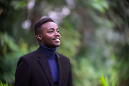 Handsome african business man in trendy formal black suit. Guy with beard wearing blue long sleeve or sweaterの写真素材