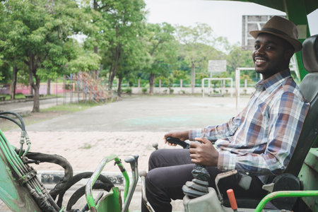 African worker driving heavy construction equipment backhoe with smile and happyの写真素材