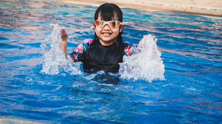 Smiling asian little girl with sunglasses in the poolの写真素材