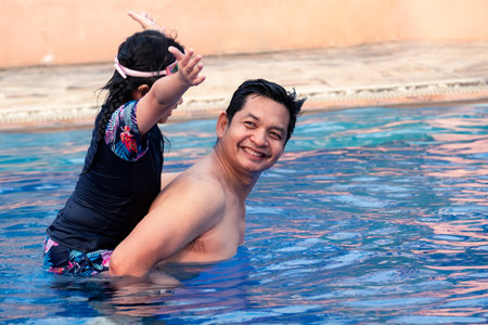 Happy father with little daughter in swimming pool at water park with smileの写真素材