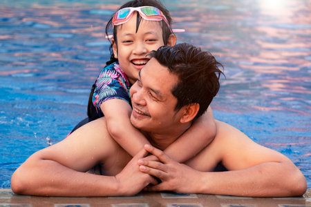 Happy father with little daughter in swimming pool at water park with smileの写真素材