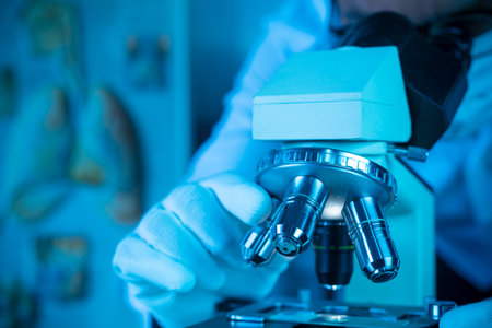 Doctor or scientist wear medical face mask and looking in microscope while working on medical research in Covid-19 or corona virus  laboratoryの写真素材