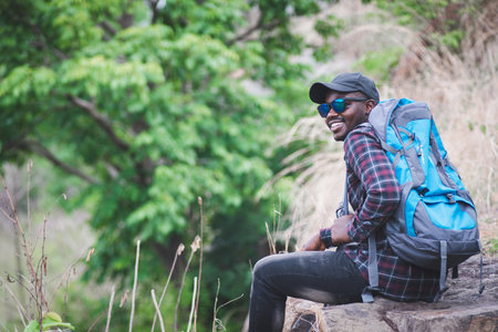 African man traveler sitting on the top of moutain with backpackの写真素材