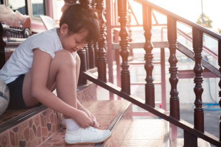 Little child girl tying shoelaces for exercise and play footballの写真素材