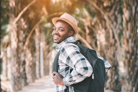 African man traveler carrying backpack walking through the park