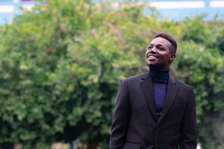 Handsome african business man standing in trendy formal black suit. Guy with beard wearing blue long sleeve or sweaterの写真素材