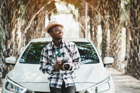 Happy traveler african man on the road with white car and holding camera