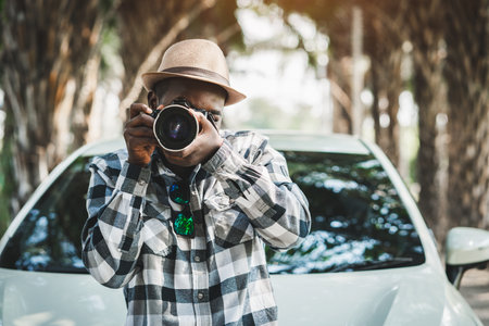 Photographer african traveler  man on the road with white car and taking photo  cameraの写真素材