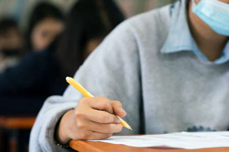 Students wearing mask for protect  virus  and doing exam in classroom with stressの写真素材