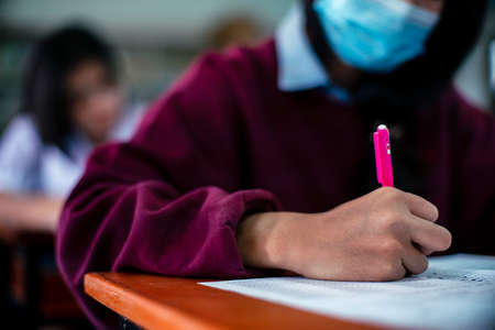 Students wearing mask for protect  virus  and doing exam in classroom with stressの写真素材
