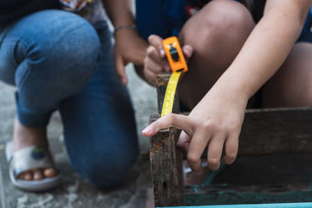 The childens is repairing wooden with a pencil and tape measureの写真素材