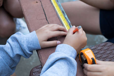 The childens is repairing wooden with a pencil and tape measureの写真素材