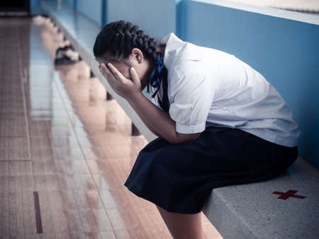 Asian young girl student sitting alone with sad feeling at schoolの写真素材