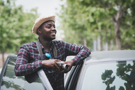 African man traveler is holding camera and standing with carの写真素材