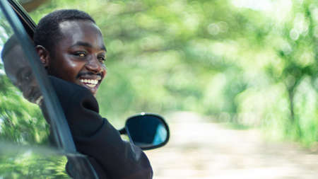 African business man driving and  smiling while sitting in a car with open front window.16:9 styleの写真素材