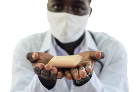 Isolated of African man holding and show a piece of soap with wearing face mask on white backgroundの写真素材