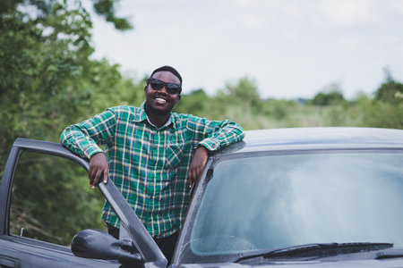 African man wearing sunglasses and smiling with a carの写真素材