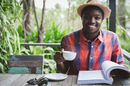 African man reading a book with holding a hot coffee.World book day Conceptの写真素材