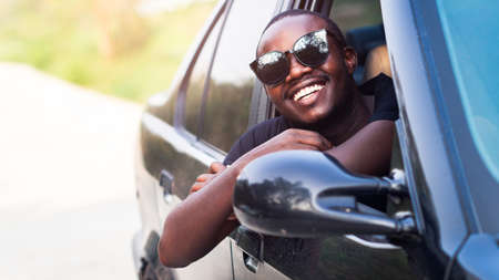 African man driver wearing sunglasses and smiling while sitting in a car.16:9 styleの写真素材