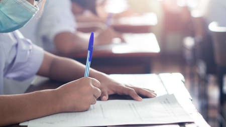 Students taking exam and writing answer in classroom with wear face mack. Education test conceptの写真素材