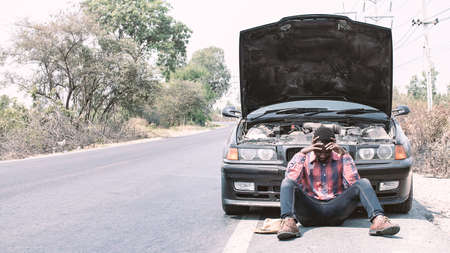 Serious african man sitting at the broken carの写真素材