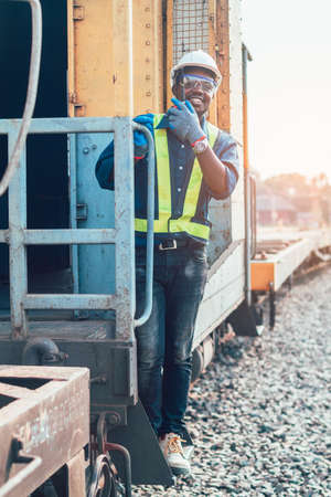 African man engineer holding radio communication or walkie talkie and hanging out of the  trainの写真素材