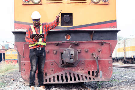 African engineer   control a the train on railway with using tablet and talking by radio communication or walkie talkieの写真素材