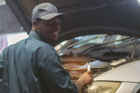 African maintenance male checking car, service via insurance system at automobile repair and check up centerの写真素材
